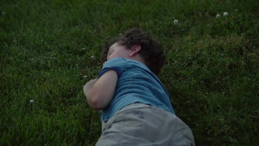 A boy rolls around on his lawn