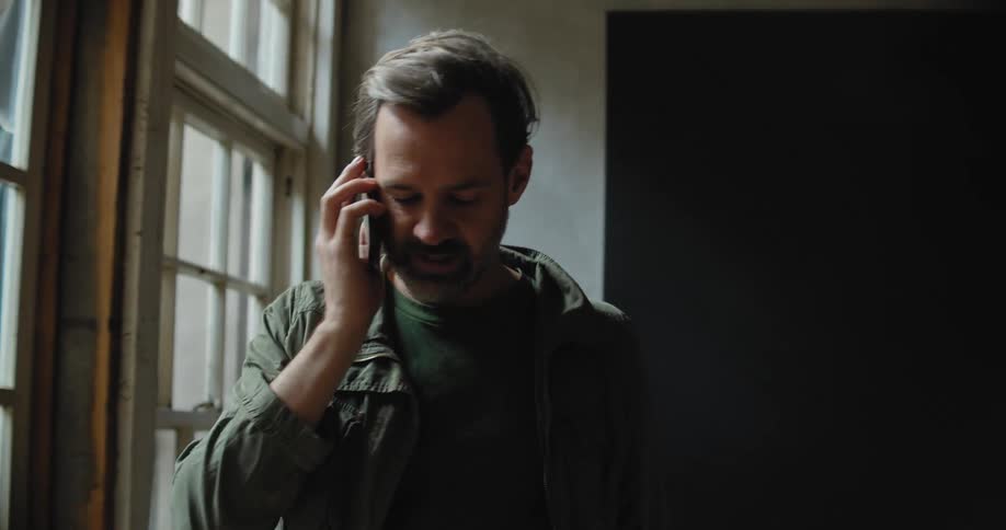 A man talking on a phone staring out a window