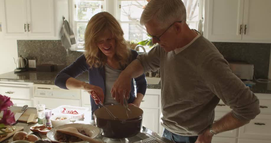 Mature couple cooking dinner togheter in the kitchen at home