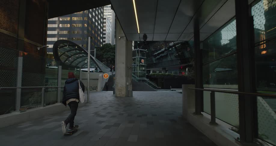 Man carrying a bag rides a skateboard in the city at morning