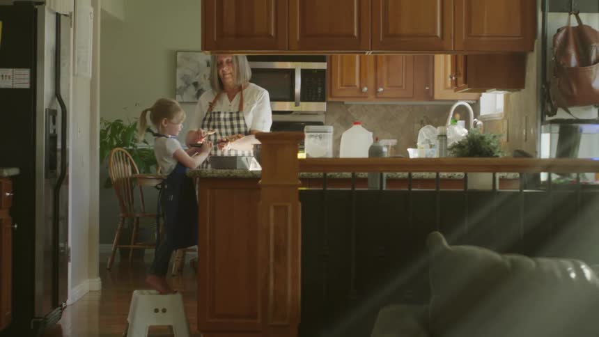 A grandmother bakes at home with her granddaughter