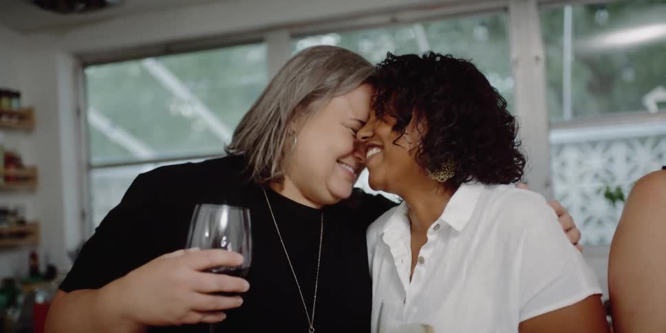 Three friends are drinking wine together and hugging