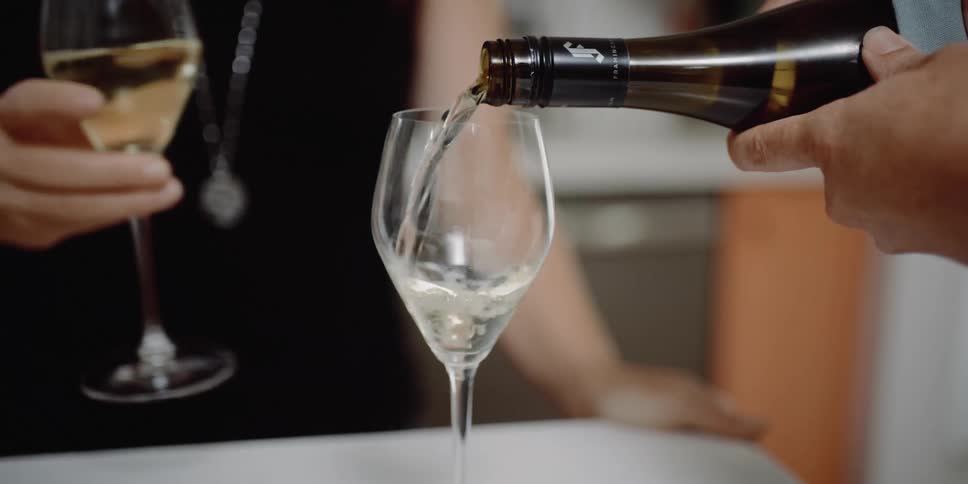 Woman pours wine into glass and another woman takes the glass
