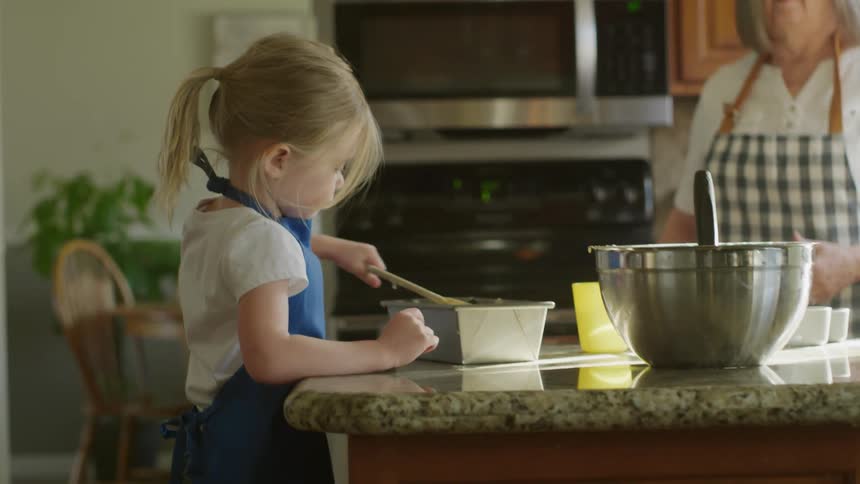 Girl preparing a cake with her grandmother in the kitchen at home