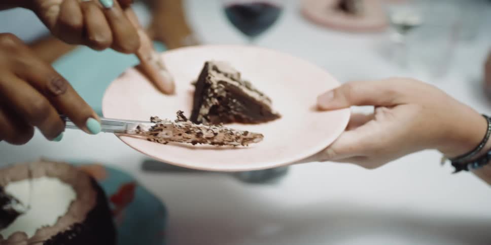 A woman serving a piece of cake on a plate on a table