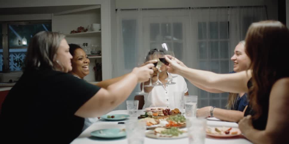 Group of friends toasting with wine over dinner at home