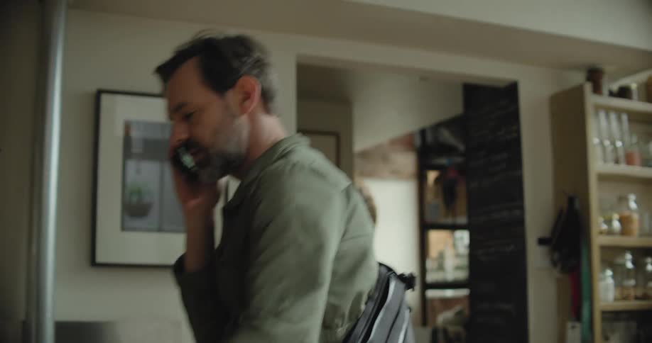 Man talks on mobile phone and gestures while searching through house