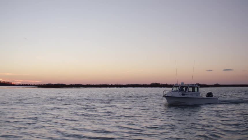 A boat driving slowly at sunset