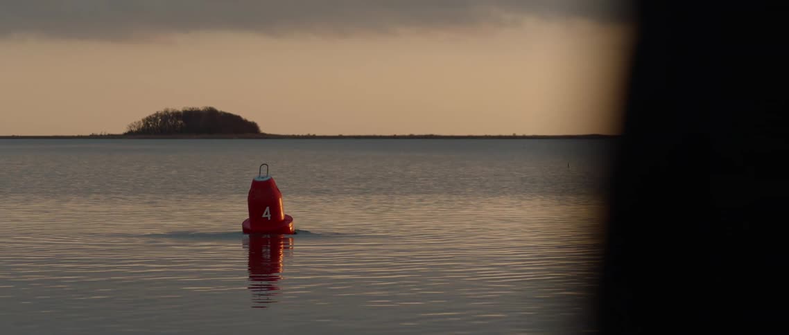 A red buoy is knocked over by something mysterious underwater
