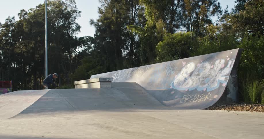 A man rides a inline skates onto a pyramid shaped jump at a skate park