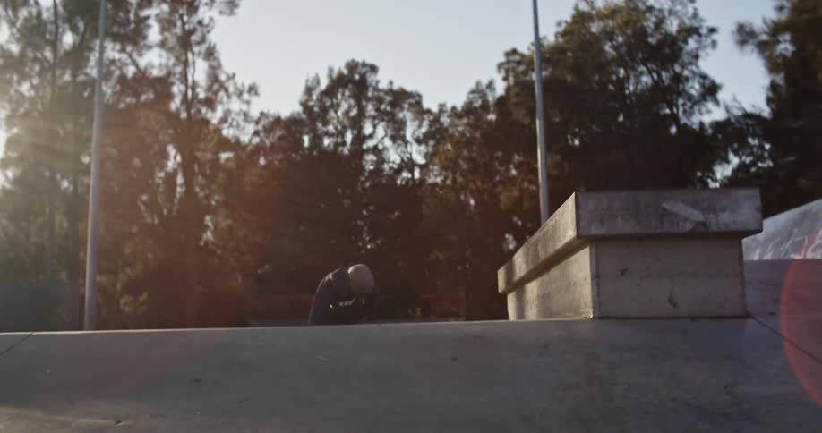 A person with inline skates skating in a skate park with trees the sky and clouds in the background