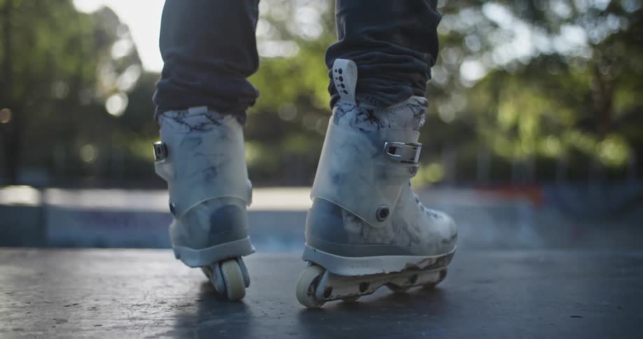 A person in roller skates stands in a skate park during the day