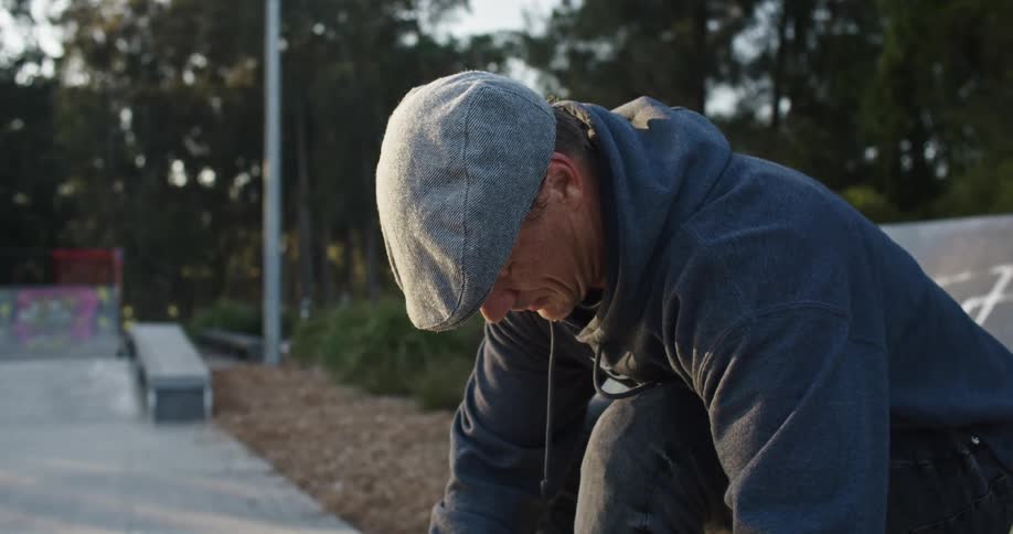 A man sits on a park bench and ties his shoes