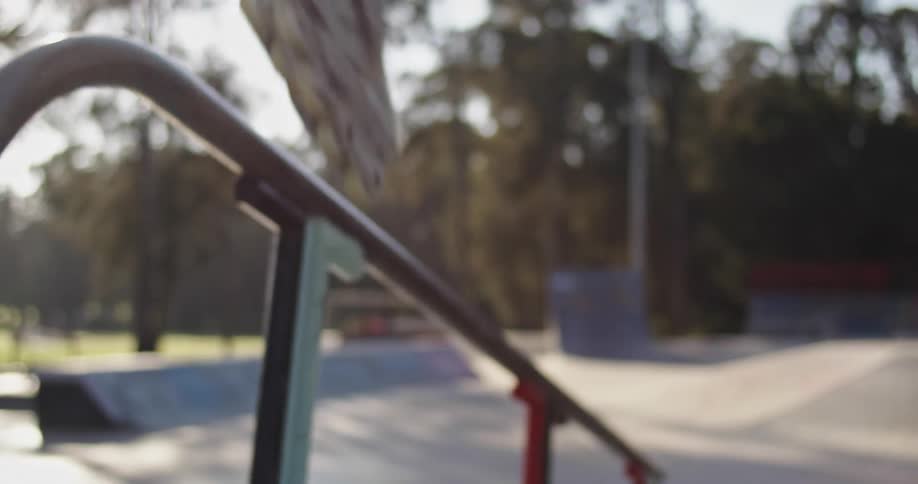 A man rides his skates down a rail in a skate park