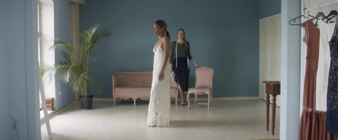 Tailor looking a client testing a long white dress