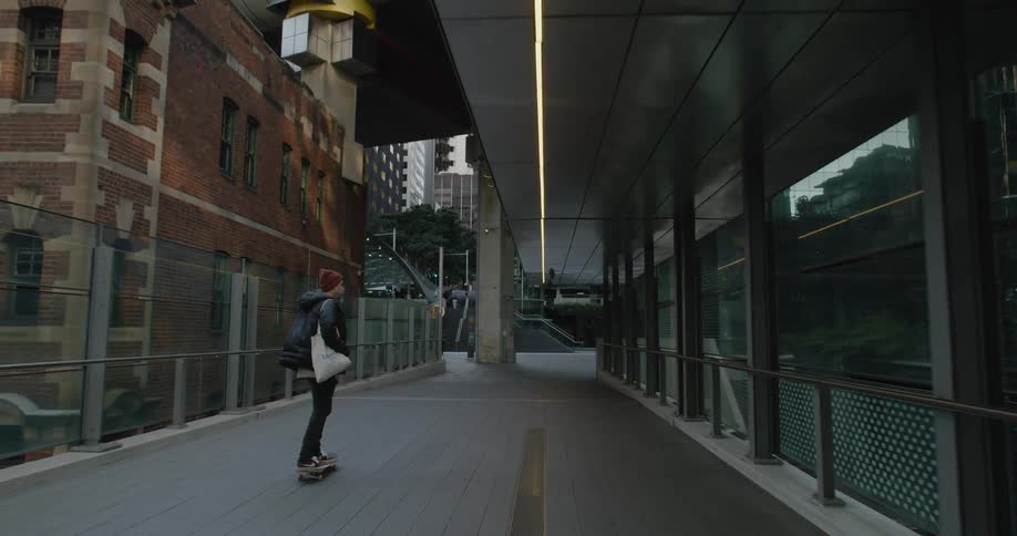 A teenager skateboarding on a walkway in the city
