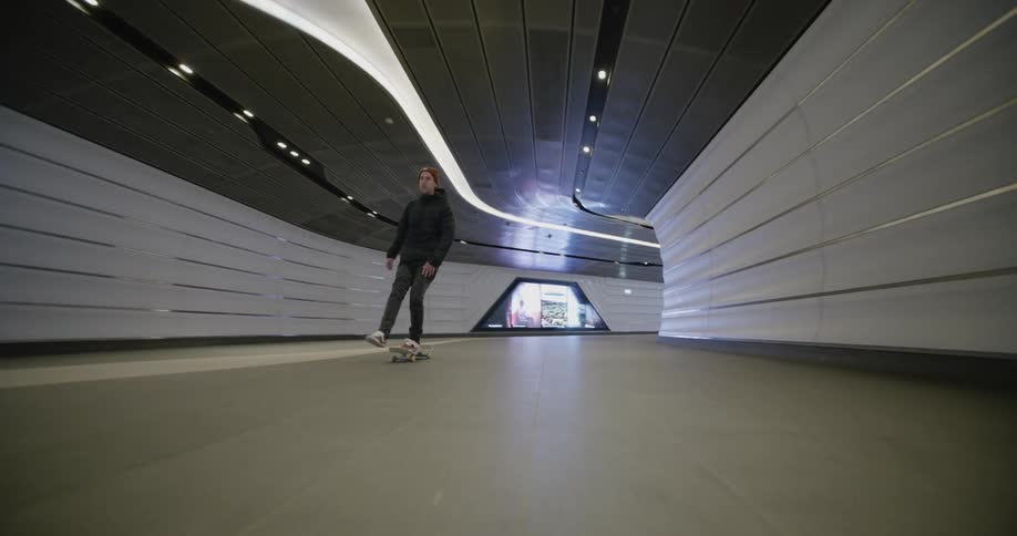 A man is skateboarding through a tunnel