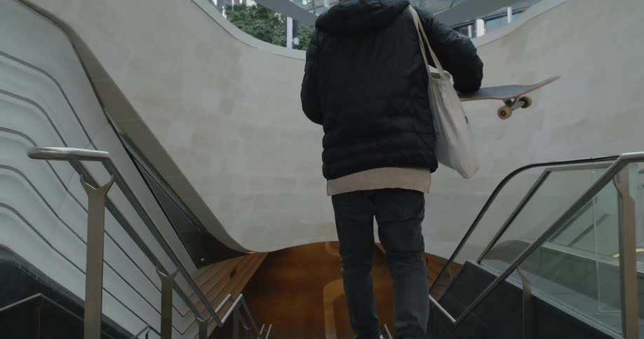 A man is walking down a flight of stairs with his skateboard