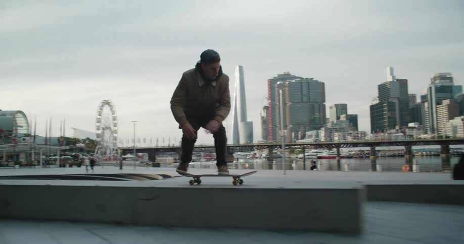 Young man driving a skateboard on the city next to the harbor
