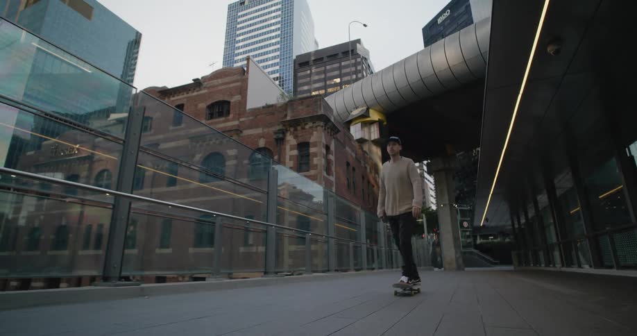 A man skating on a skateboard with buildings the sky and clouds in the background