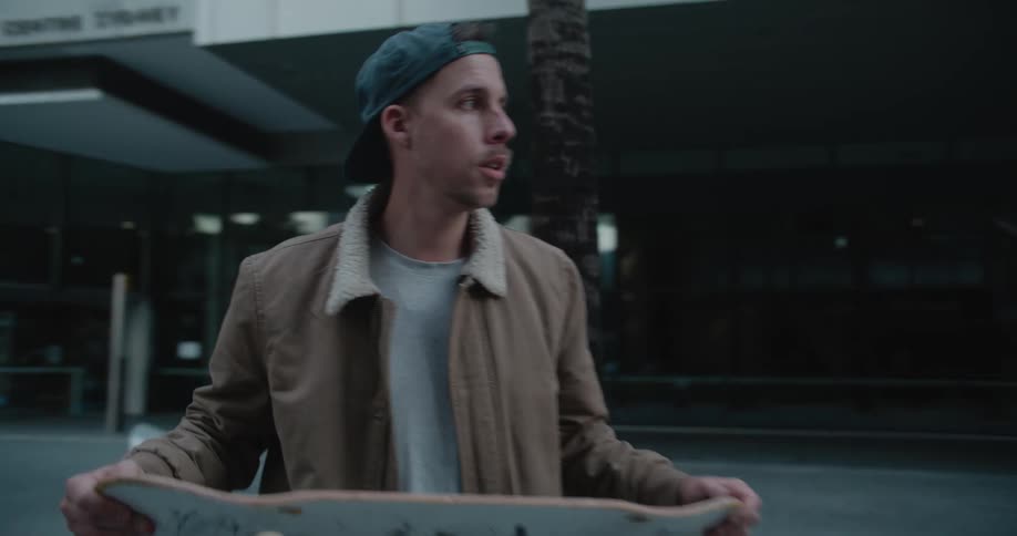 A man skateboards through an empty city sidewalk