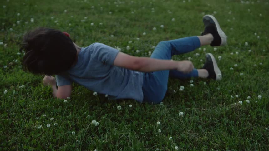 Child rolling on the green grass at morning