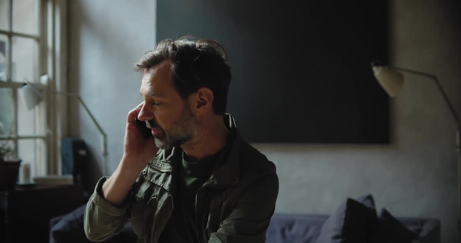 Man talking on a phone inside a dimly lit room
