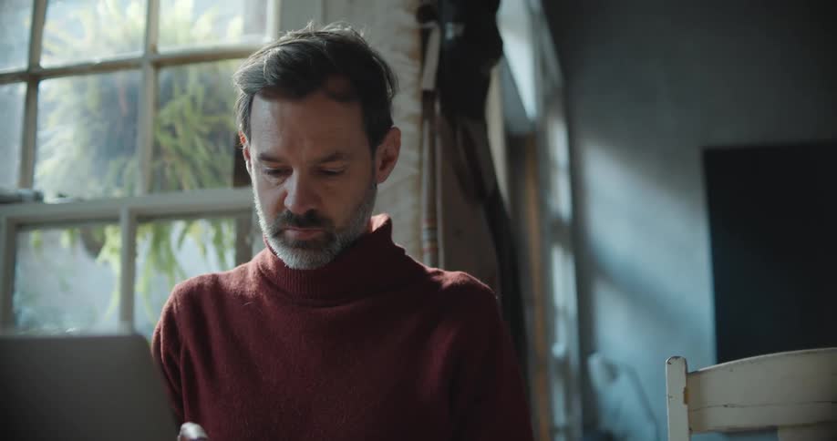 A man is sitting in a room looking down