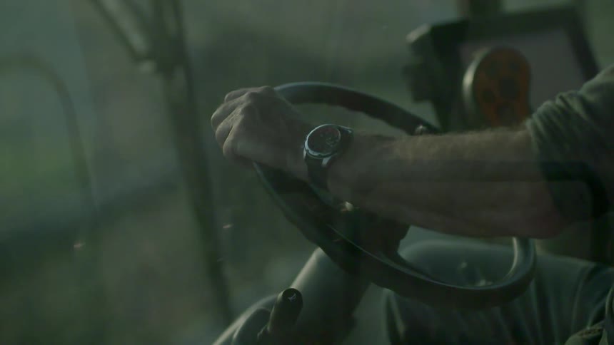 A man is steering a wheel of a farm vehicle