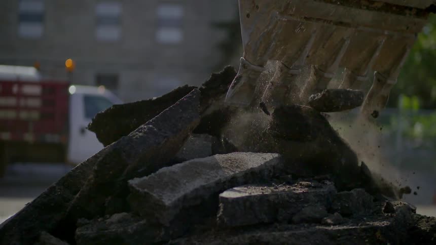 An excavation machine is dropping gravel onto a pile