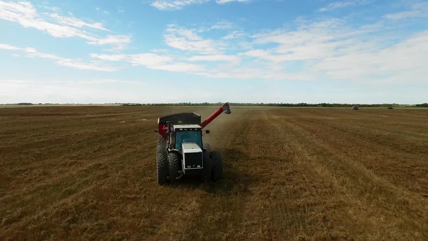 A tractor moves through farmland in the day time