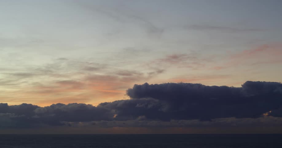 Dark clouds loom over the ocean at sunset