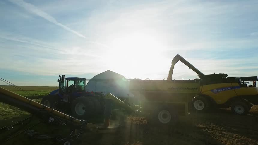 Farm equipment working at sunset