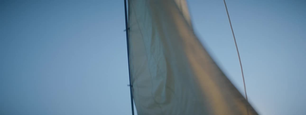 A boat sailing out on a lake with the sail flapping in the wind