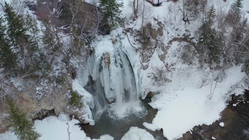 Water pours down a waterfall into a river in this snow covered wilderness area