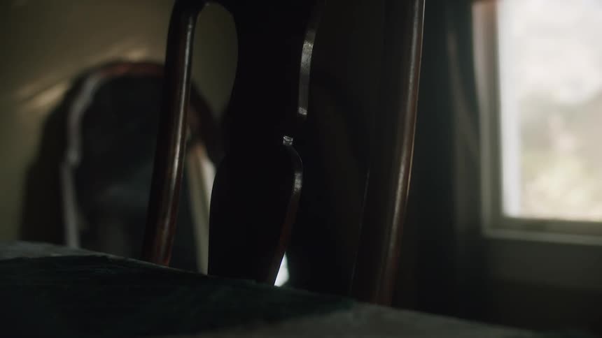 Chair in front of a table next to a window inside a dimly lit room