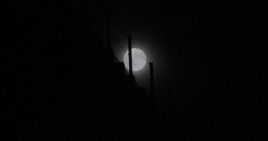 A fence with the sky and the moon in the background
