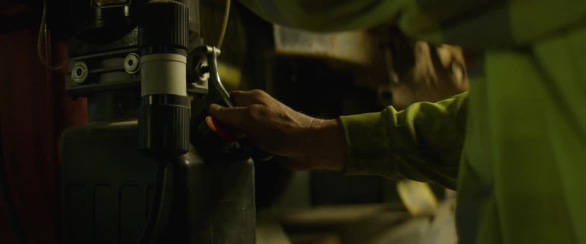 A man holds onto the handle of a piece of black and steel machinery