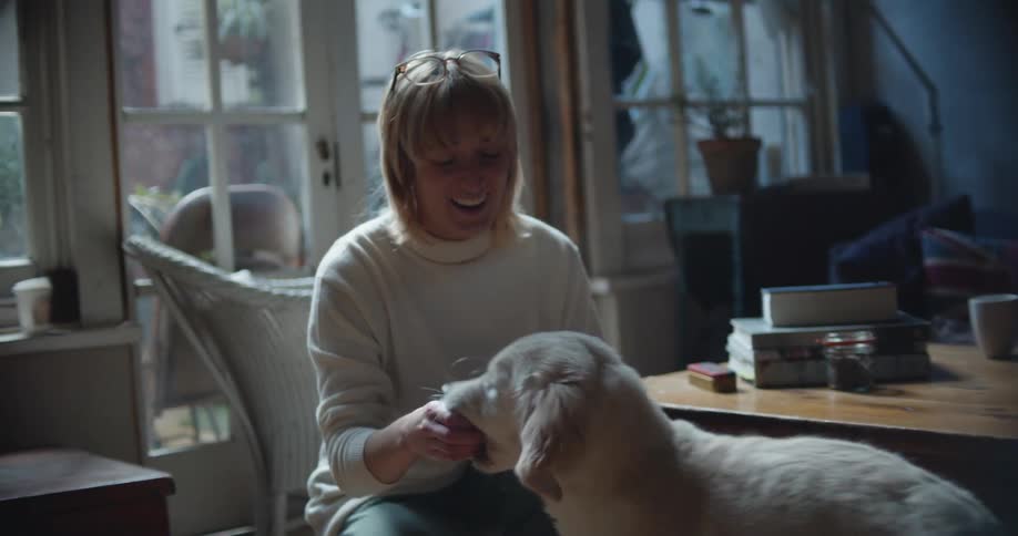 A woman is playing with her dog and sitting indoors