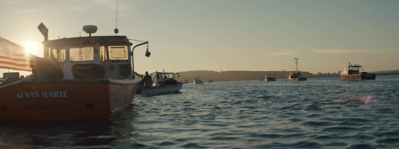 Small boats traveling in the ocean next to a pier during the day