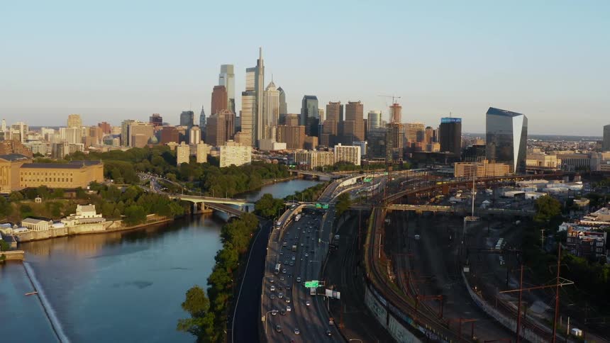 Traffic travels along a freeway running alongside a river in a metropolis during the day