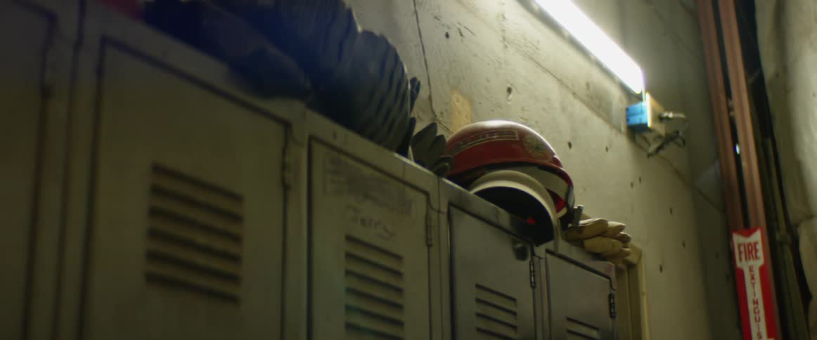 Helmets and other sports equipment sit on top of lockers in a dingy locker room