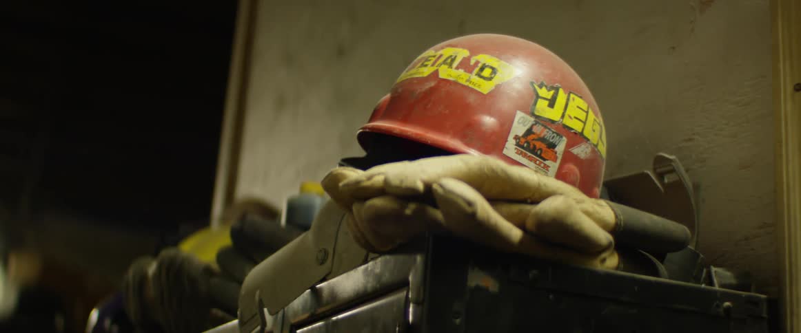 Red helmet with stickers sits on gloves on metal furniture