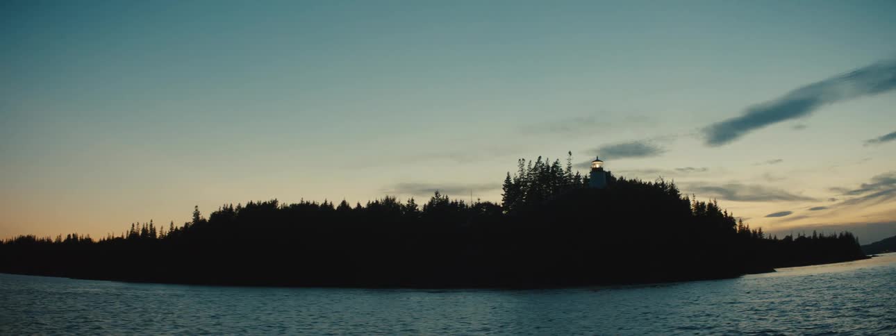 A silhouette of a coast from the ocean in the evening