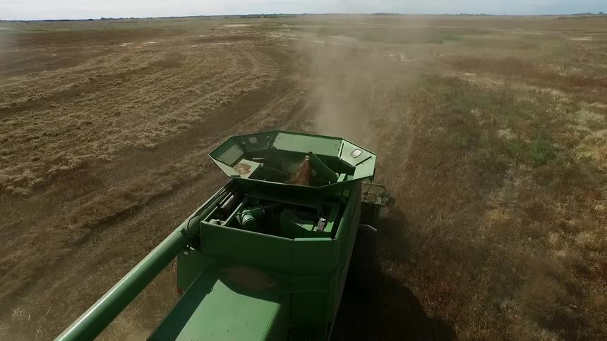 A large green piece of equipment works in a field