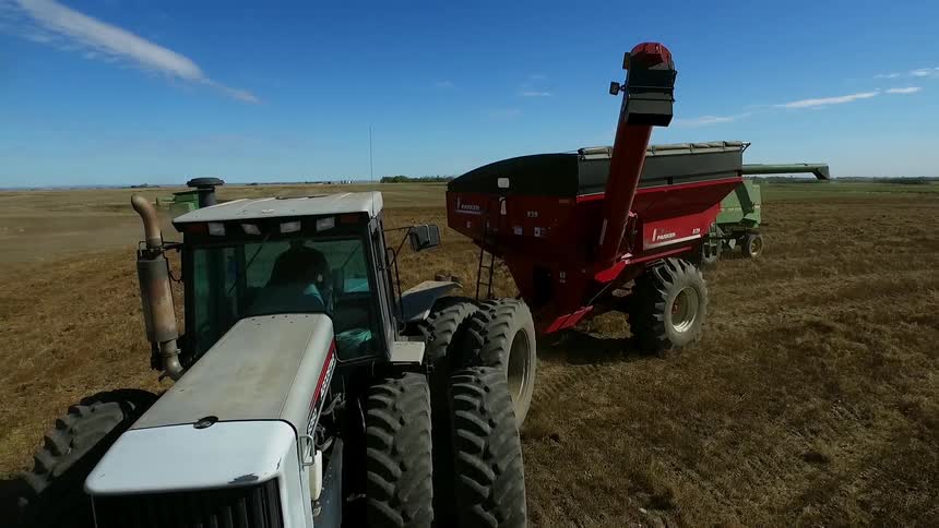 Farm machinery rolls down a field
