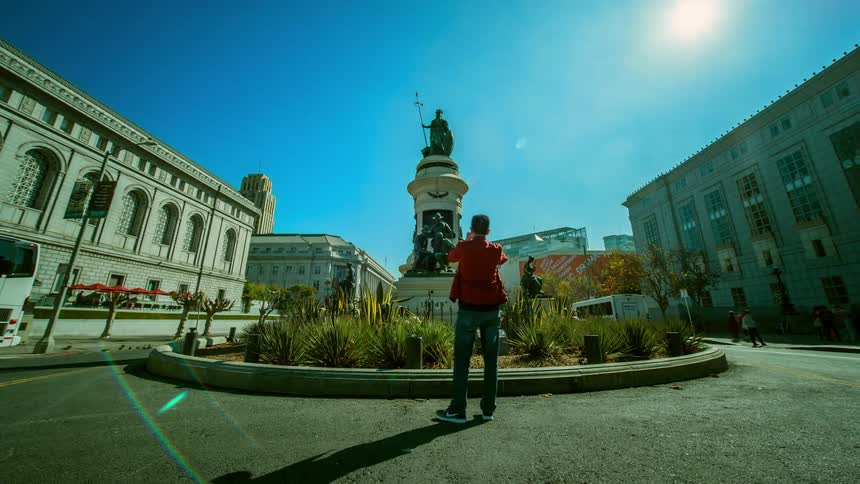 Various people having their pictures taken in front of statue