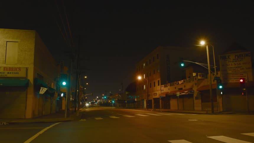 Closed businesses on a quiet street with cars driving in the distance