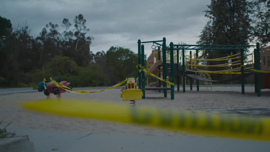 A look at sandy public park with swings that are taped with caution sign