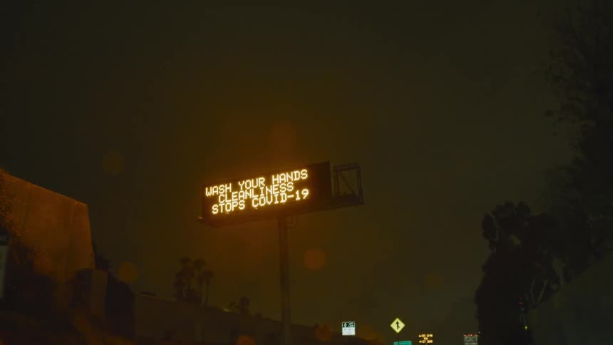 A lit up notification sign seen through the window of a car in a city